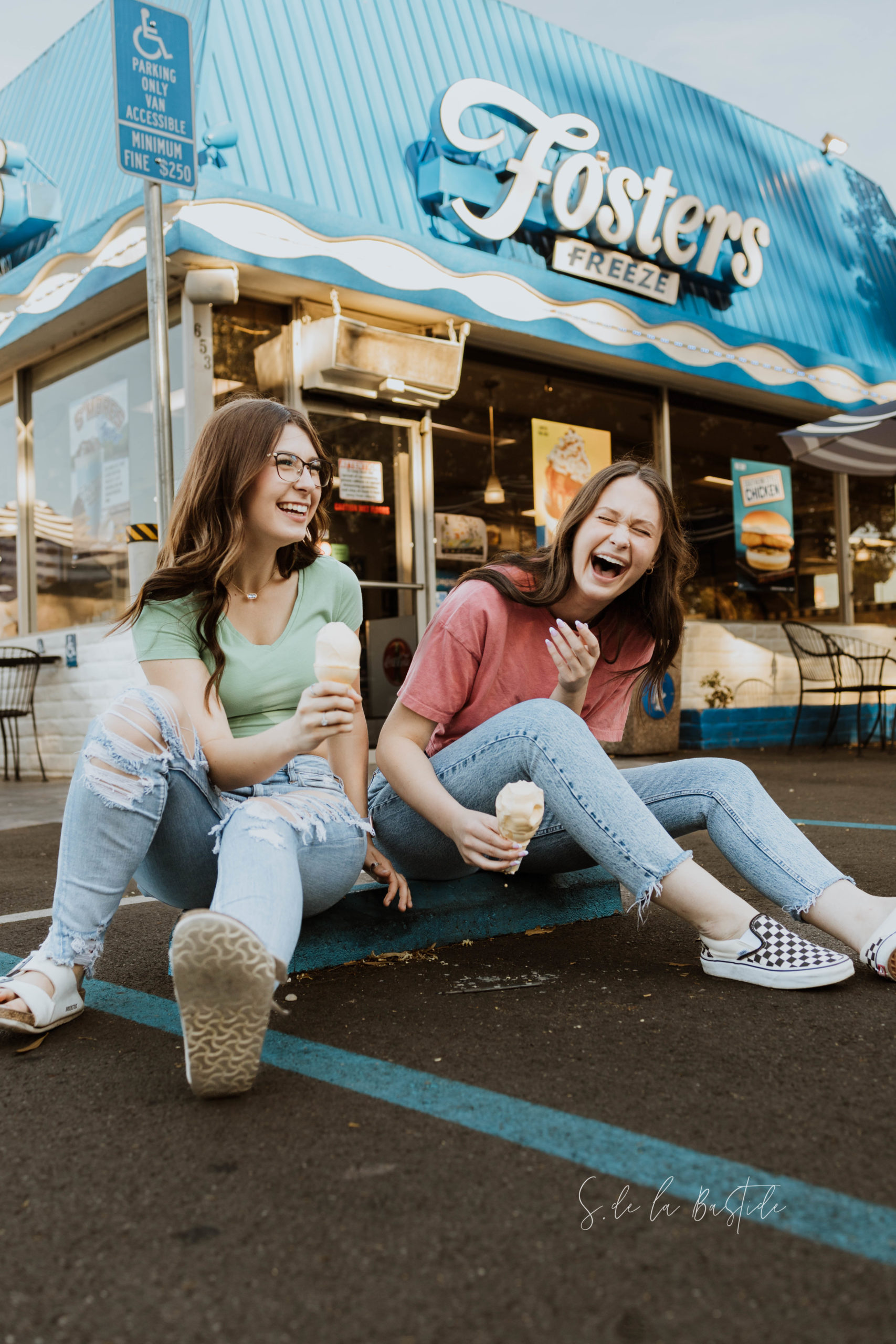 Senior Portraits in Vacaville at Foster's Freeze.  Two best friends enjoying ice cream cones and laughing together.  Wearing crop tops with jeans and checkered vans.